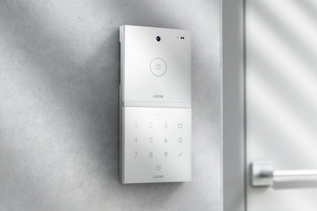Loxone Intercom in white on a grey wall beside a door, shown with NFC Code Touch, sold separately